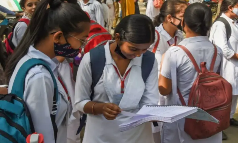 Girls searching answers in book after examination.